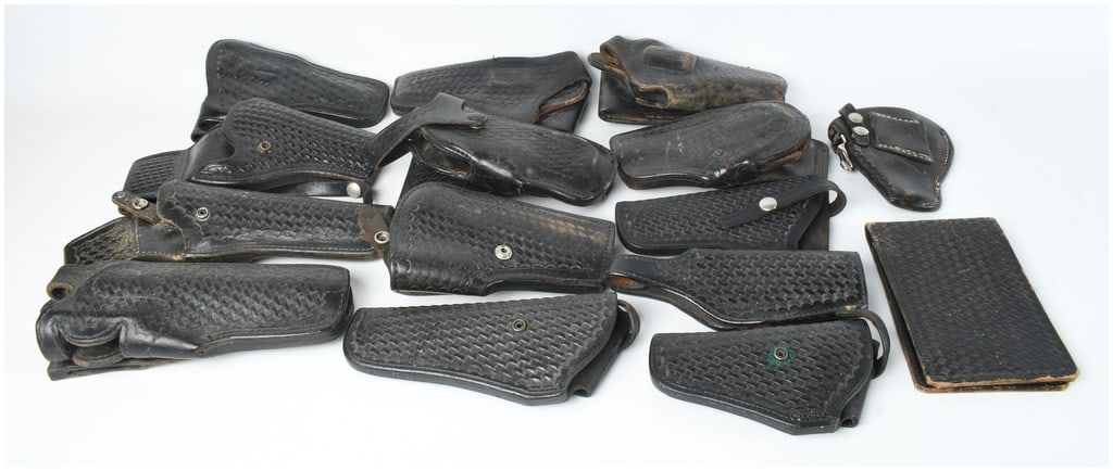 A Collection of 15 Leather Holsters and Accessories: This lot comprises fifteen items including various firearm holsters and a document cover or wallet, all finished in black leather. Many of the pieces feature a professional basket-weave stamped patter