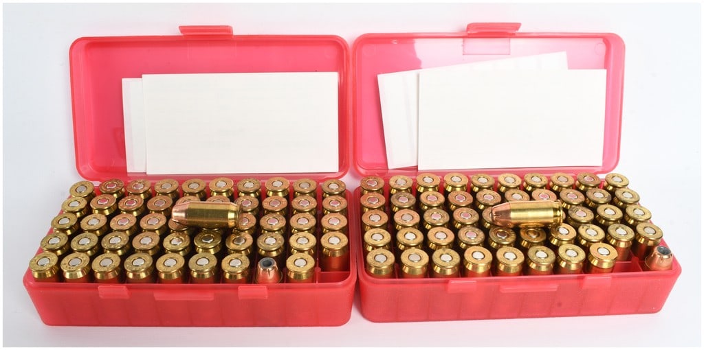 A Lot of 100 Rounds of Winchester and Remington Jacketed Hollow Point Ammunition .45 Auto: This lot consists of 100 rounds of .45 Auto ammunition featuring copper-jacketed hollow point projectiles seated in brass casings. The cartridges are presented in two red plastic MTM Case-Gard flip-to