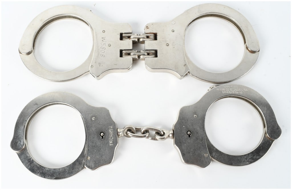 Two Pairs of Peerless Handcuffs Including Model 300 and Hinged Model: This lot features two pairs of professional-grade nickel-plated steel handcuffs manufactured by the Peerless Handcuff Company. The first pair is a hinged restraint model utilizing a triple-hinge desig