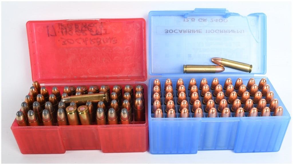 A Lot of 93 Rounds of .30 Carbine Ammunition and 7 Empty Brass Casings: This lot consists of 93 rounds of .30 Carbine ammunition and 7 empty brass casings organized within two translucent plastic storage boxes. The blue container holds 52 rounds of 110-grain full metal ja
