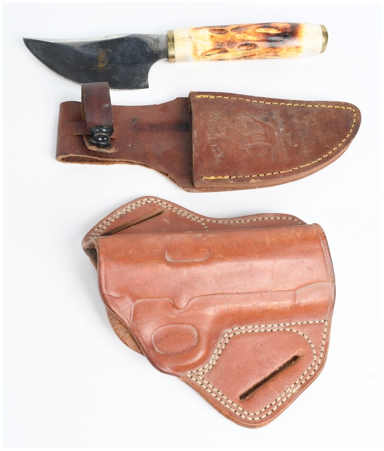 Two Items Including a Bone Collector Skinning Knife with Sheath and an Armadillo Leather Holster: This lot consists of two primary items: a fixed-blade hunting knife with a coordinating belt sheath and a separate leather handgun holster. The skinning knife features a dark-finished, upswept blade s