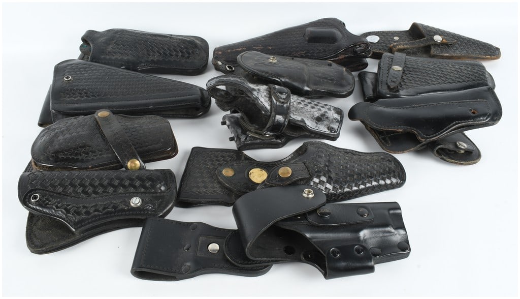 A Collection of 12 Assorted Black Leather Service and Duty Holsters: This lot consists of twelve assorted black leather holsters primarily configured for service and duty use. The collection features a variety of designs including basketweave tooled and plain leather f