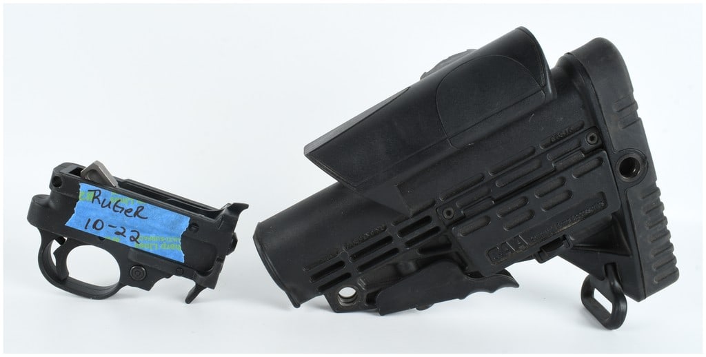 Two Firearm Accessories Including a Ruger 10-22 Trigger Assembly and a CAA CBS16 Buttstock: A Ruger 10-22 trigger assembly and a CAA Command Arms Accessories CBS16 adjustable buttstock. The trigger assembly features a black polymer housing with a cross-bolt safety and a red indicator ring. A
