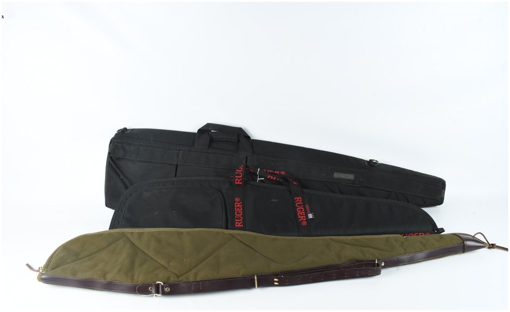 A Trio of Soft Sided Rifle Cases Including Ruger and Assault Systems: This lot consists of three soft-sided rifle cases. The first is a black nylon tactical-style rifle case featuring two large external accessory pockets with flap closures, dual webbed carry handles,