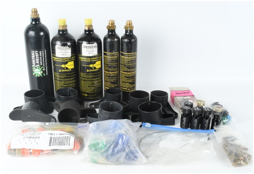 A Collection of Paintball CO2 Cylinders, On-Off Adapters, and Maintenance Accessories: A collection of paintball hardware comprising five CO2 cylinders and multiple maintenance components. The cylinder group features one large black aluminum tank with JF Paintball & Airsoft branding fro