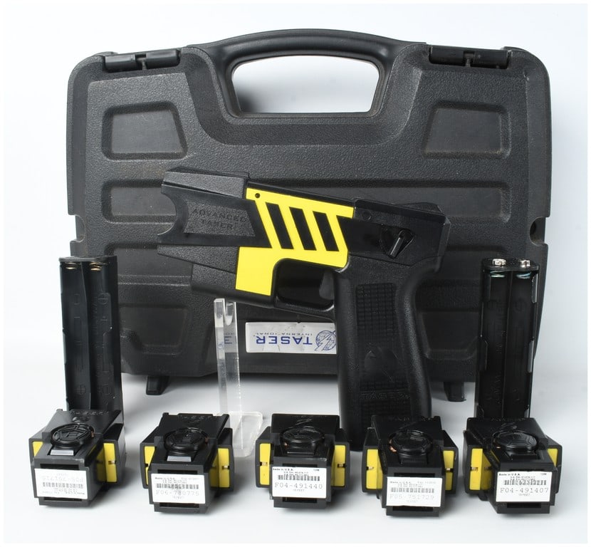 Advanced TASER M26 Electronic Control Device with Cartridges and Accessories: This lot features an Advanced TASER M26 electronic control device manufactured by Taser International. The unit is constructed with a black textured polymer body, designed with a grip angle and form f
