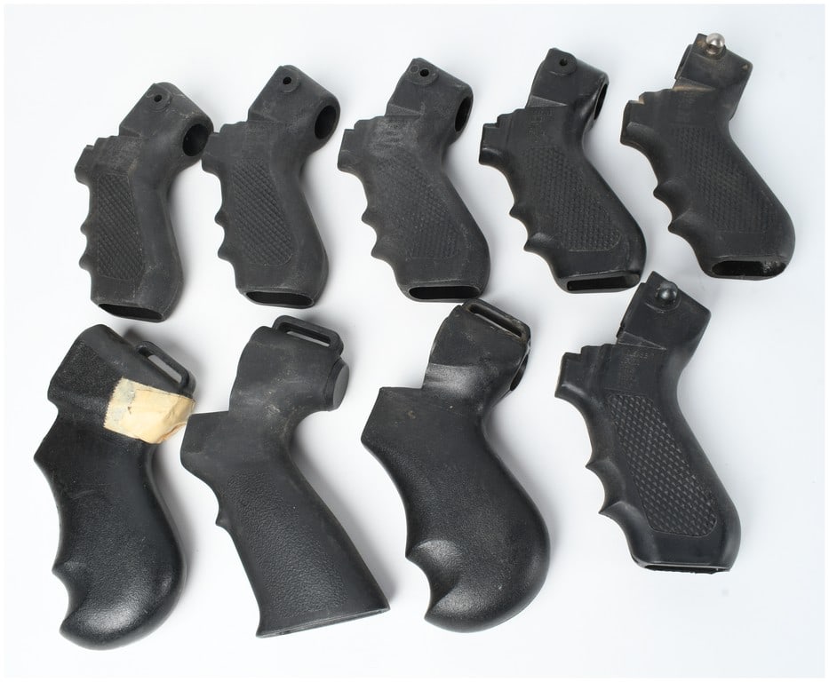 Nine Black Polymer Pistol Grips: A collection of nine black polymer pistol grips designed for various firearm platforms. The group includes several ergonomic styles featuring finger grooves and textured diamond-patterned side panels.