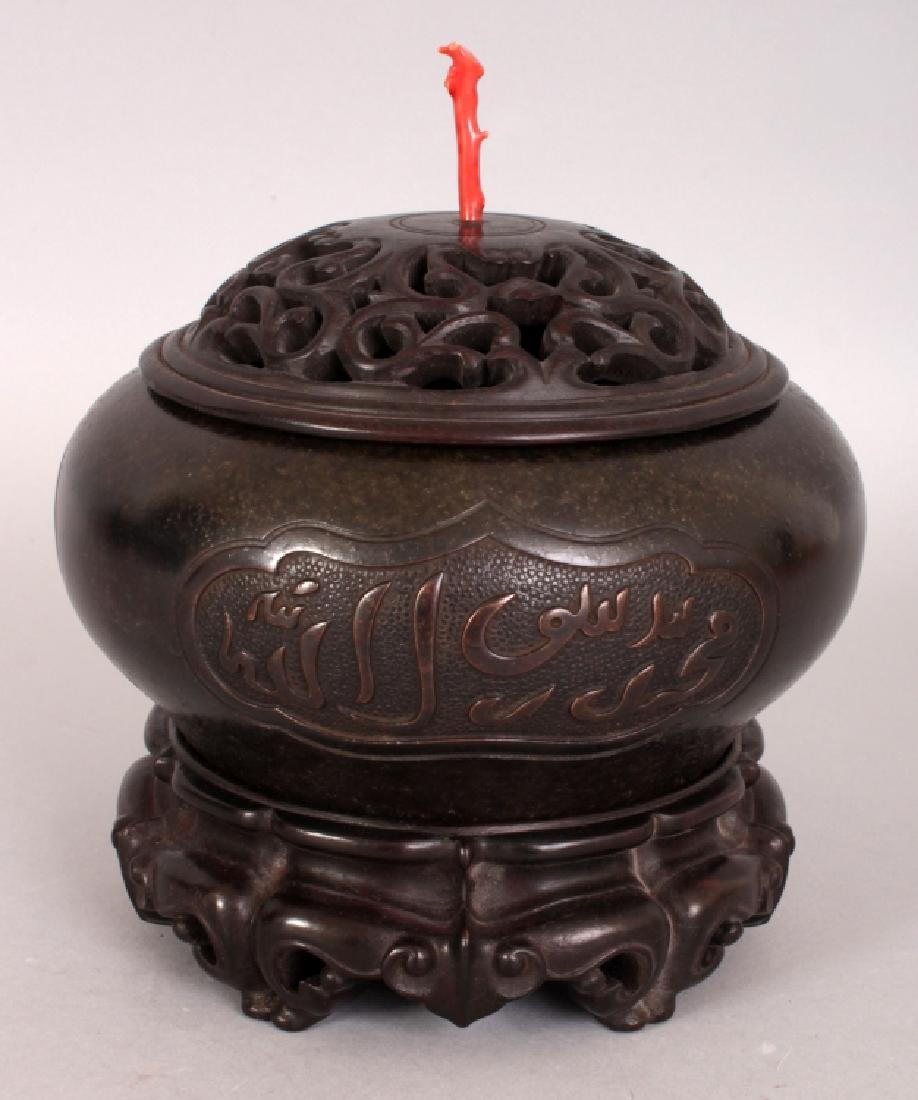 A CHINESE ISLAMIC MARKET BRONZE CENSER, together with a: A CHINESE ISLAMIC MARKET BRONZE CENSER, together with a fitted wood stand and a fitted pierced wood cover set with a coral finial, the censer itself weighing 2.53Kg, the sides decorated with panels of