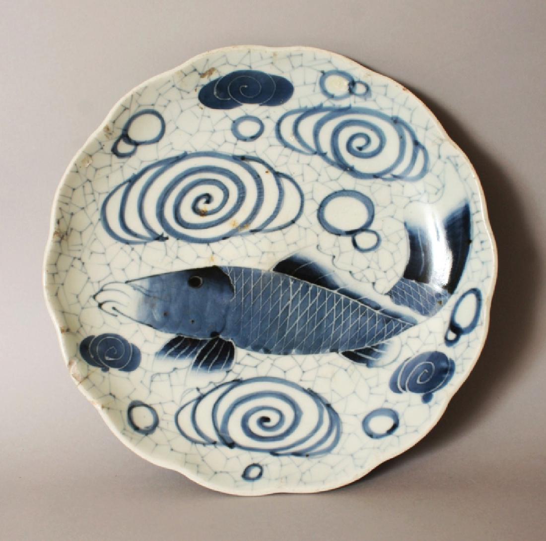 AN 18TH CENTURY JAPANESE EDO PERIOD BLUE & WHITE: AN 18TH CENTURY JAPANESE EDO PERIOD BLUE & WHITE PORCELAIN DISH, with a scalloped rim, painted with a swimming fish, the base with six spur marks, 11.1in diameter.