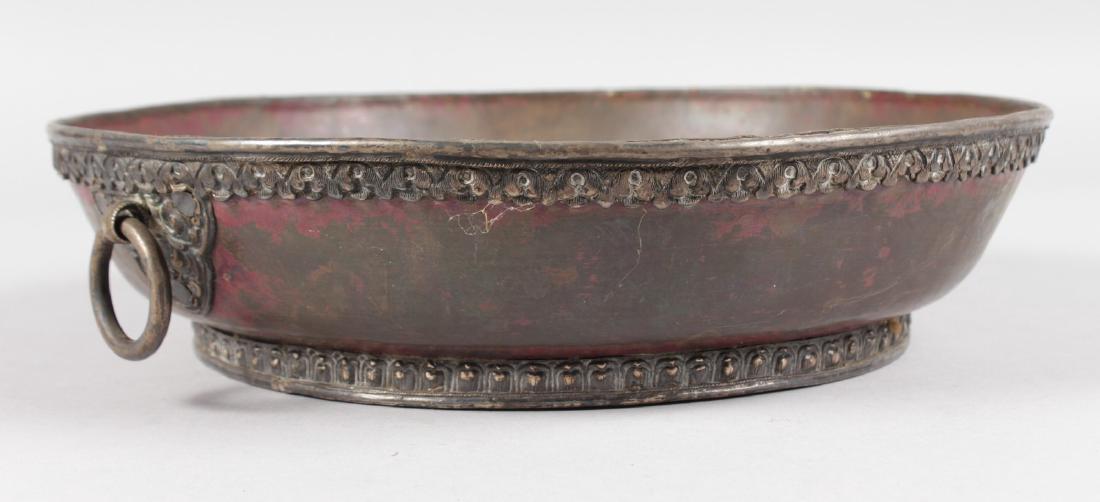 AN ISLAMIC CIRCULAR HAMMERED COPPER BOWL with two ring: AN ISLAMIC CIRCULAR HAMMERED COPPER BOWL with two ring handles. 10ins diameter.