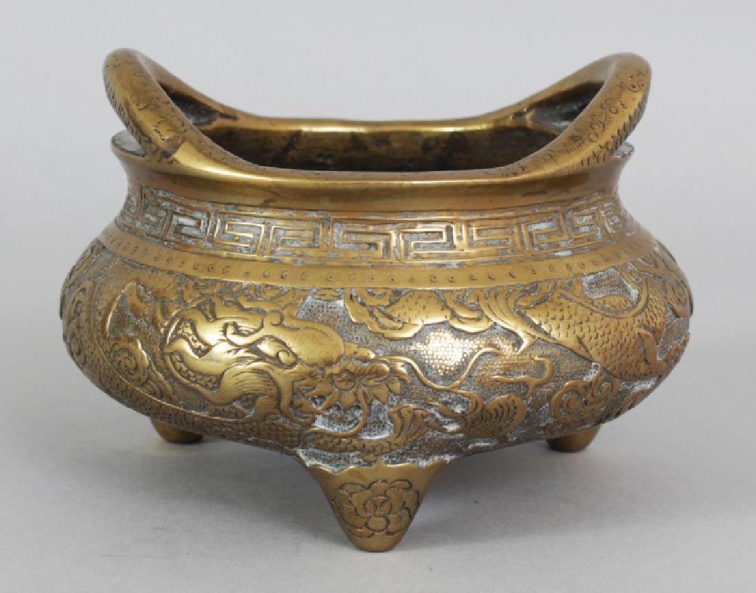 AN EARLY 20TH CENTURY CHINESE POLISHED BRONZE TRIPOD: AN EARLY 20TH CENTURY CHINESE POLISHED BRONZE TRIPOD CENSER, weighing 960gm, the sides cast in relief with a dragon and a phoenix, the base with a six-character Xuande mark, 5in wide at widest point &
