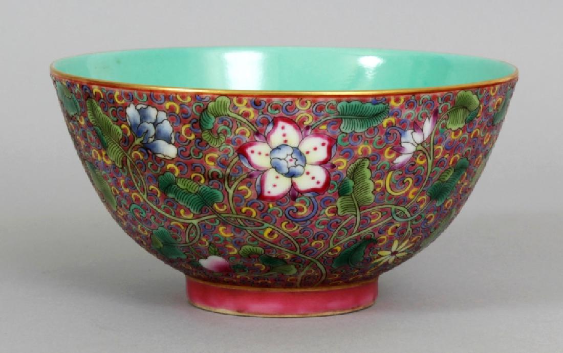 A GOOD QUALITY CHINESE FAMILLE ROSE PORCELAIN BOWL,: A GOOD QUALITY CHINESE FAMILLE ROSE PORCELAIN BOWL, decorated to the exterior sides with dense scrolling foliage reserved on a pink ground, the base with a Qianlong seal mark, 6.1in diameter & 3.1in h