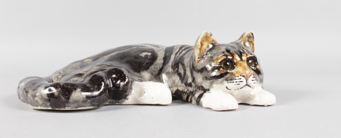 A RECLINING POTTERY CAT by WINSTANLEY.  Signed.  No. 6. (1 of 6)