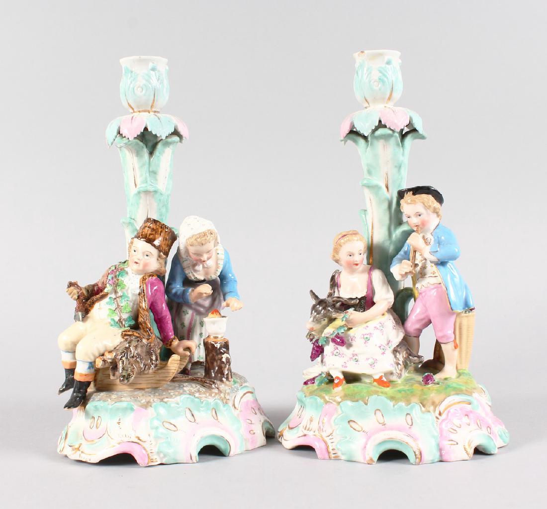 A PAIR OF AUGUSTUS REX PORCELAIN CANDLESTICKS, the: A PAIR OF AUGUSTUS REX PORCELAIN CANDLESTICKS, the bases with children and a goat. Mark in blue. 27cms high.