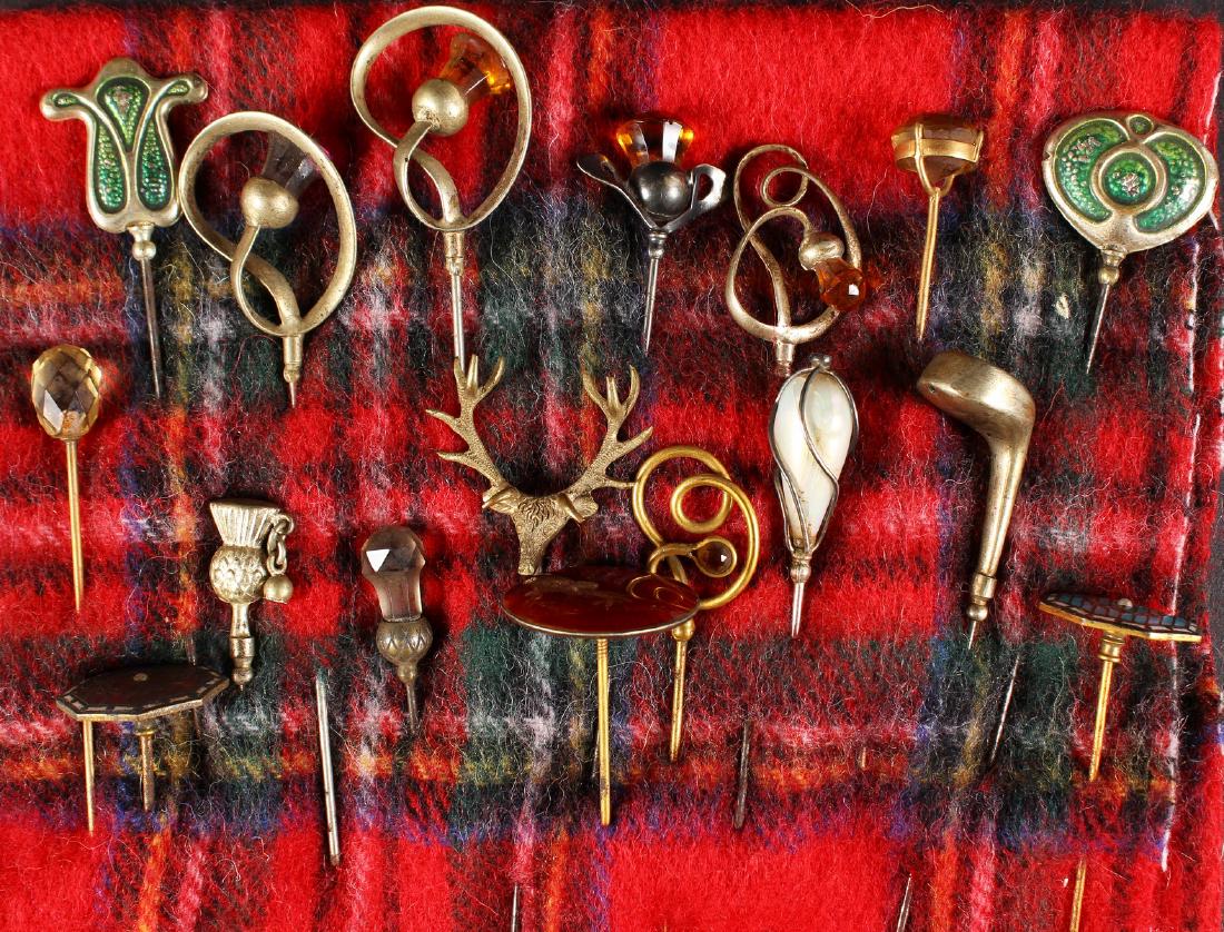 A COLLECTION OF SEVENTEEN VICTORIAN AND EDWARDIAN HAT: A COLLECTION OF SEVENTEEN VICTORIAN AND EDWARDIAN HAT PINS on a tartan cloth.