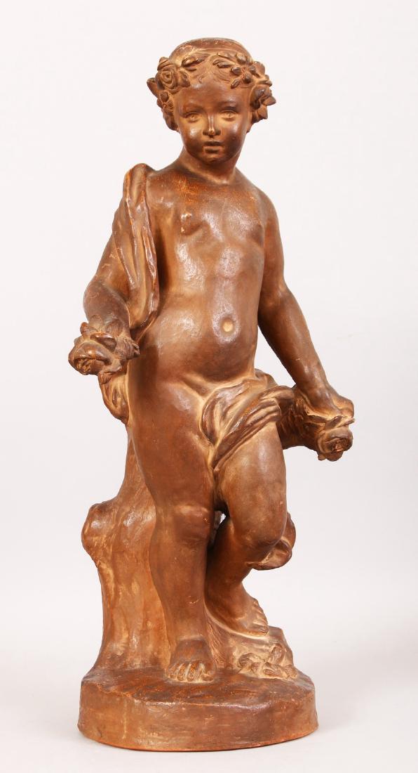 AFTER THE ANTIQUE A SUPERB TERRACOTTA STANDING CUPID,: AFTER THE ANTIQUE A SUPERB TERRACOTTA STANDING CUPID, clad in a robe and standing on a circular base. 20ins high.