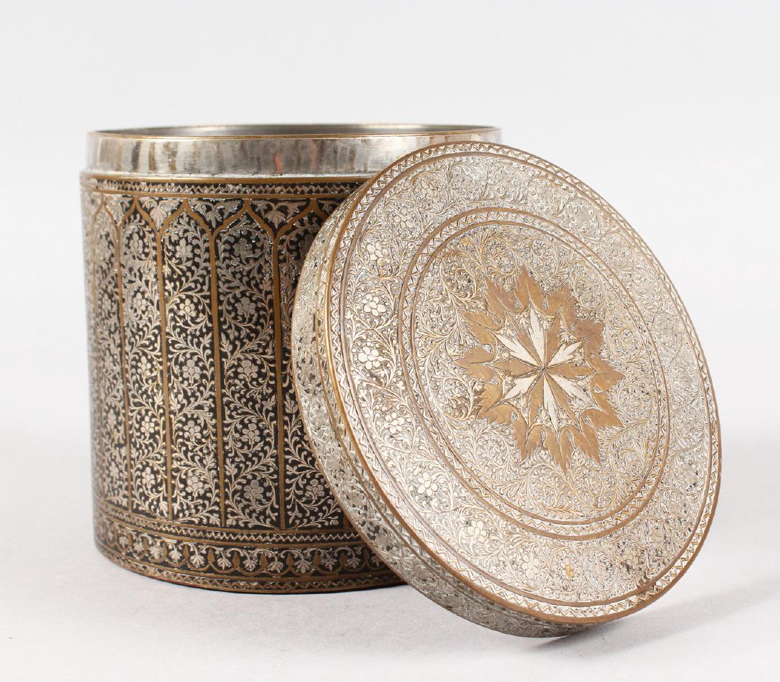 AN ISLAMIC CIRCULAR SILVER INLAID METAL BOX AND COVER.: AN ISLAMIC CIRCULAR SILVER INLAID METAL BOX AND COVER. 5.5ins high.