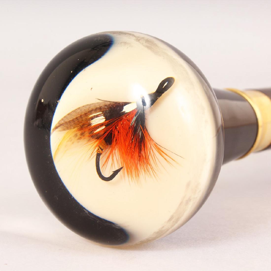 A SUPERB EDWARDIAN STYLE FLY FISHING WALKING CANE, the: A SUPERB EDWARDIAN STYLE FLY FISHING WALKING CANE, the Perspex handle inset with a salmon fishing fly. 39ins long.