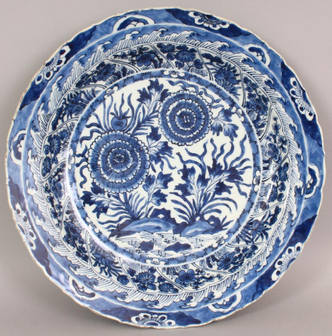 A GOOD CHINESE KANGXI PERIOD BLUE & WHITE PORCELAIN: A GOOD CHINESE KANGXI PERIOD BLUE & WHITE PORCELAIN DISH, circa 1700, with a barbed edge rim, painted to its centre in a good tone of underglaze-blue with a garden scene of flowers and rockwork, the b