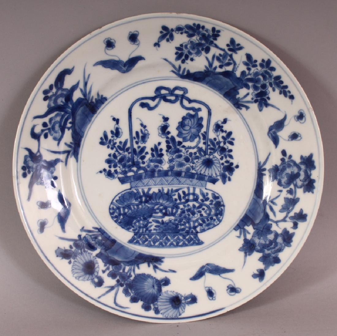 A CHINESE KANGXI PERIOD BLUE & WHITE PORCELAIN PLATE,: A CHINESE KANGXI PERIOD BLUE & WHITE PORCELAIN PLATE, circa 1700, painted to its centre with a basket of flowers, the rim with foliage and rockwork, the base with a ting censer mark, 10in diameter.