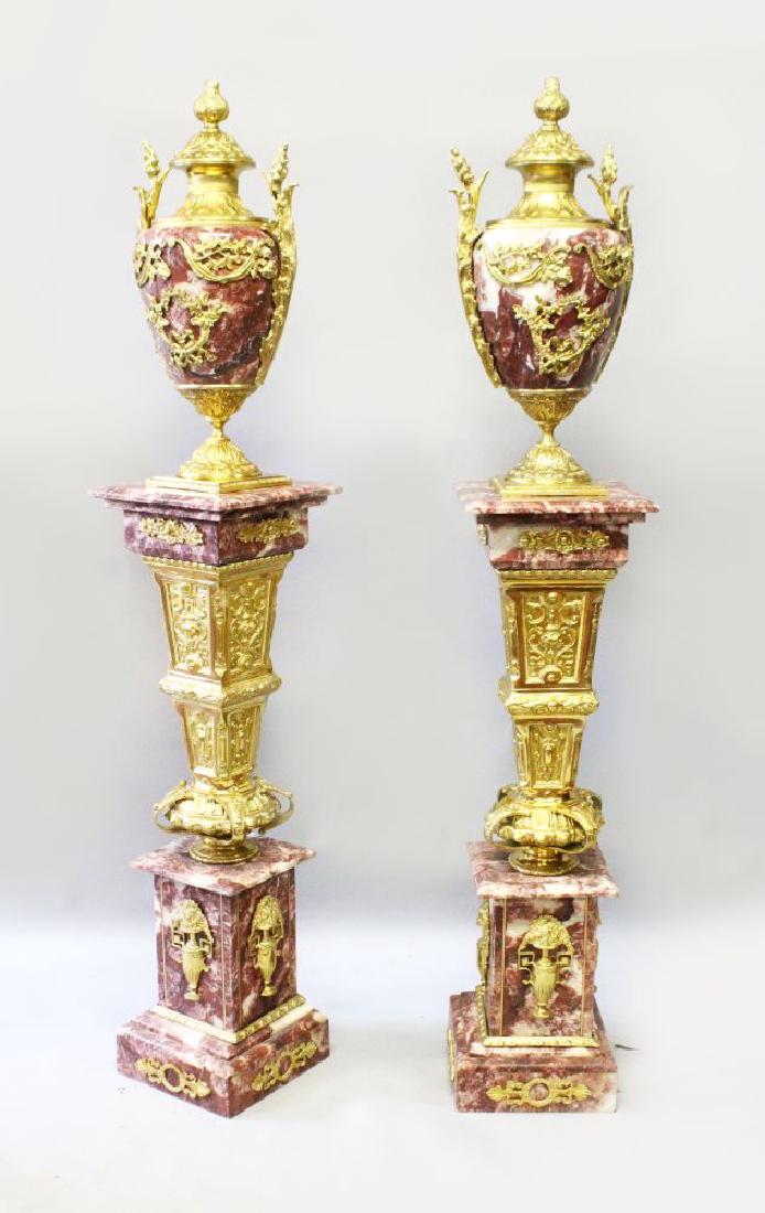 AN IMPRESSIVE PAIR OF RED VARIEGATED MARBLE AND ORMOLU: AN IMPRESSIVE PAIR OF RED VARIEGATED MARBLE AND ORMOLU MOUNTED PEDESTALS AND URNS, with extensive ormolu mounts, gilt bronze central section supporting the marble top, surmounted with the ormolu urns.