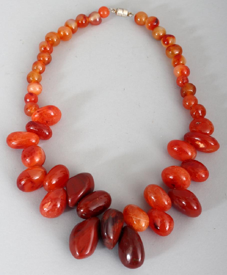 A CARNELIAN HARDSTONE NECKLACE, composed of irregular: A CARNELIAN HARDSTONE NECKLACE, composed of irregular graduated beads, approx. 19.5in long.
