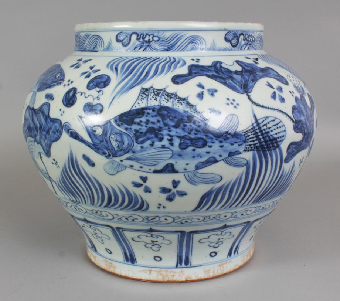 A LARGE CHINESE YUAN STYLE BLUE & WHITE PORCELAIN JAR,: A LARGE CHINESE YUAN STYLE BLUE & WHITE PORCELAIN JAR, decorated with carp swimming amidst water weeds, the base unglazed, 12.7in wide at widest point & 10.4in high.