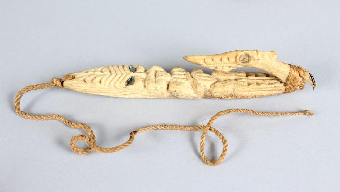 MAORI FISH HOOK, NEW ZEALAND Matau Carved bone, glass: MAORI FISH HOOK, NEW ZEALAND Matau Carved bone, glass inset mirrored eyes to the figure and barb, the barb fixed at the base and bound tightly again with muka (flax fibre) cord. Height 6ins