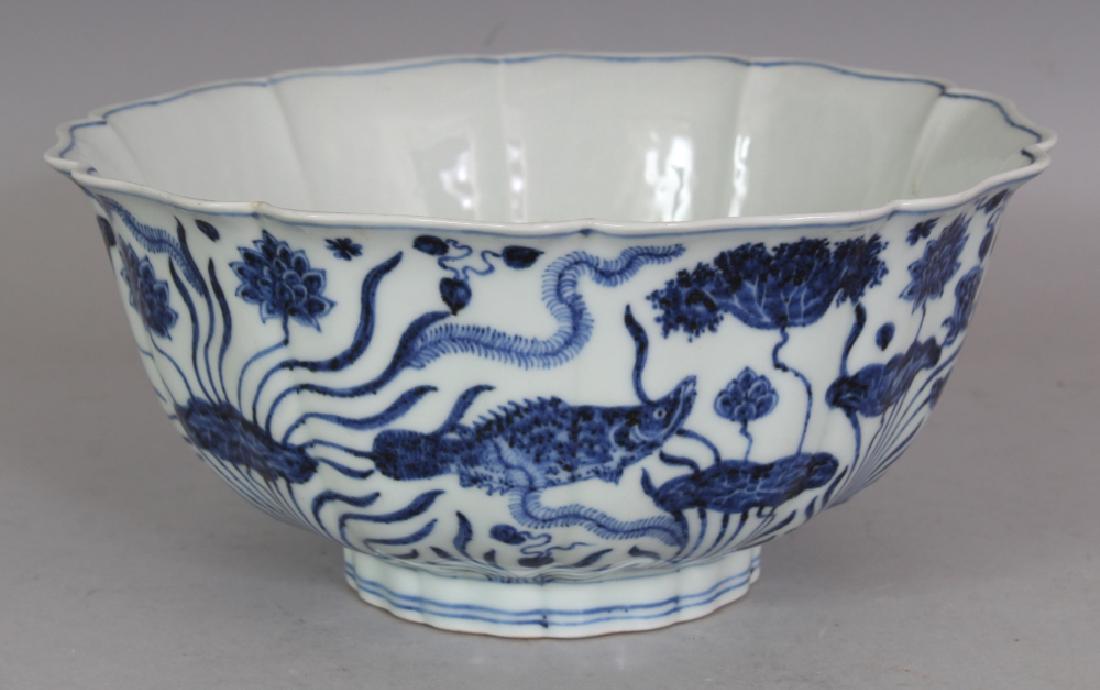 A CHINESE MING STYLE BLUE & WHITE PORCELAIN BOWL, the: A CHINESE MING STYLE BLUE & WHITE PORCELAIN BOWL, the lobed sides and interior centre decorated with fish swimming amidst lotus and water weeds, the base with a six-character Xuande mark, 9.25in diame