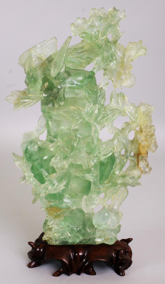 A CHINESE GREEN BOWENITE VASE & COVER, together with a: A CHINESE GREEN BOWENITE VASE & COVER, together with a fitted wood stand, the stone carved in high relief with birds and foliage, 10.25in high overall, the vase itself 9.5in high overall.