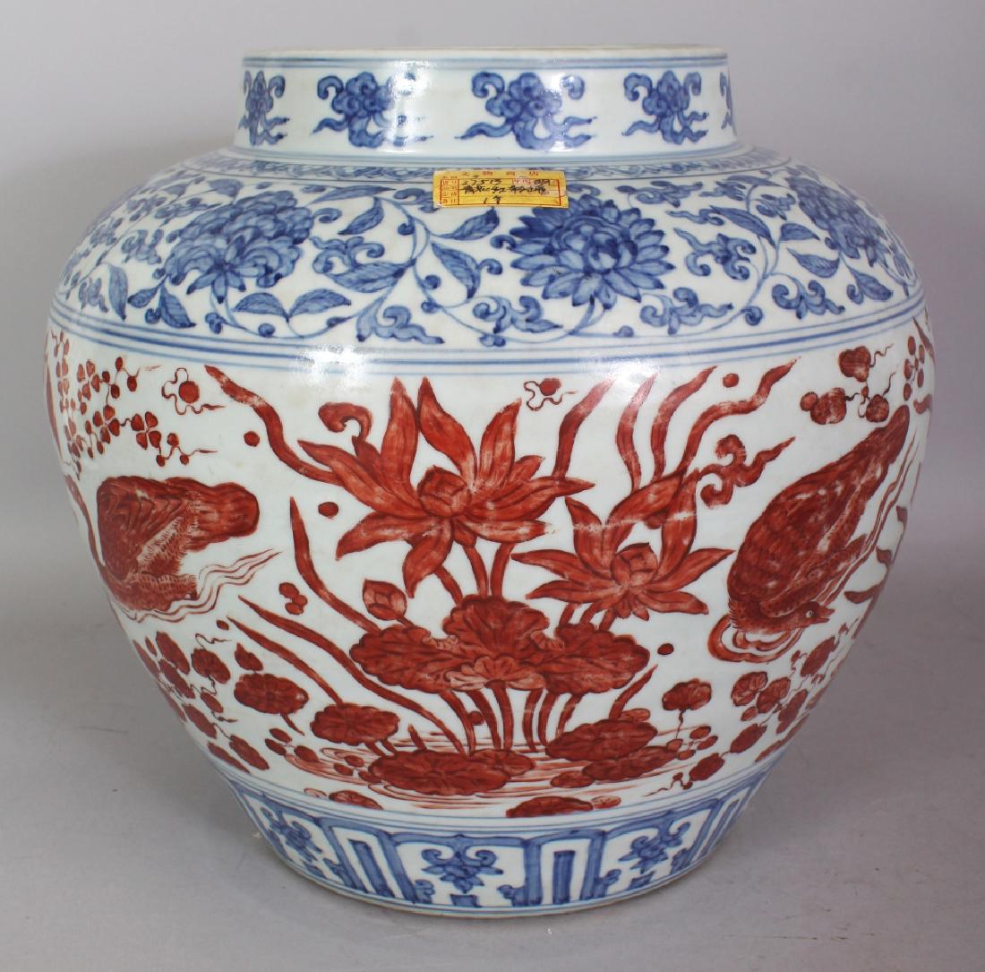 A LARGE GOOD QUALITY CHINESE MING STYLE COPPER-RED &: A LARGE GOOD QUALITY CHINESE MING STYLE COPPER-RED & UNDERGLAZE-BLUE PORCELAIN JAR, the sides decorated in copper-red with a continuous scene of ducks swimming in a lotus pond, between underglaze-blue