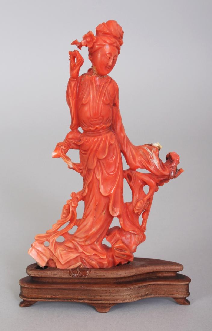 A 20TH CENTURY CHINESE CORAL CARVING OF A LADY,: A 20TH CENTURY CHINESE CORAL CARVING OF A LADY, together with a fixed wood stand, the lady standing beside a tree stump, 5.3in high.