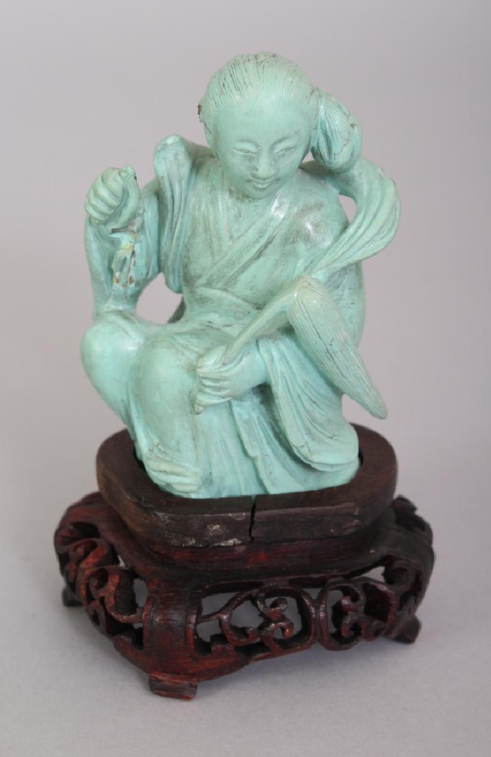 A 20TH CENTURY CHINESE TURQUOISE-STYLE MODEL OF A: A 20TH CENTURY CHINESE TURQUOISE-STYLE MODEL OF A SEATED FEMALE IMMORTAL, together with a fitted wood stand, the deity bearing a fly whisk, 3.75in high overall, the model itself 2.8in high.