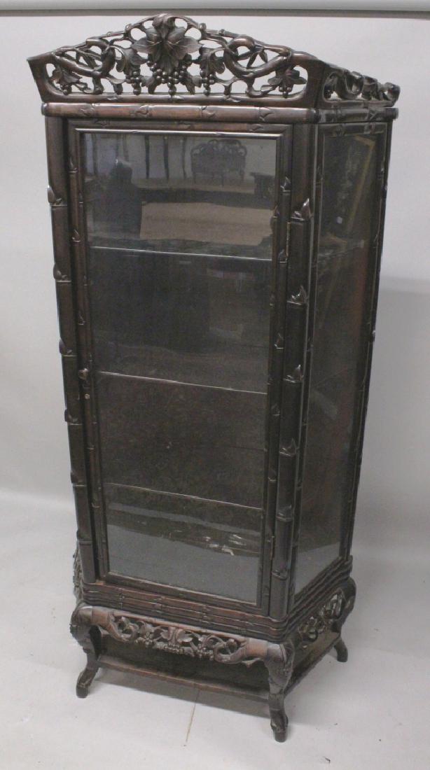 A LARGE 19TH CENTURY CHINESE CARVED HARWOOD DISPLAY: A LARGE 19TH CENTURY CHINESE CARVED HARWOOD DISPLAY CABINET, with chamfered sides and three interior shelves, surmounted with a pierced and carved leaf and vine cornice above bamboo borders to the sid
