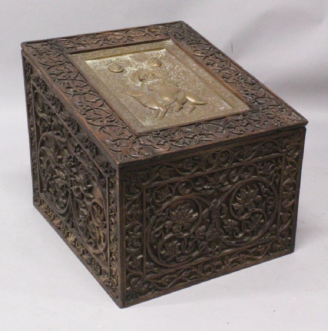 AN EARLY 20TH CENTURY INDIAN CARVED WOOD RECTANGULAR: AN EARLY 20TH CENTURY INDIAN CARVED WOOD RECTANGULAR CHEST, the sloping hinged lid inset with an embossed brass panel of Ganesha, within elaborate deeply carved scrollwork to the rim and to the sides,