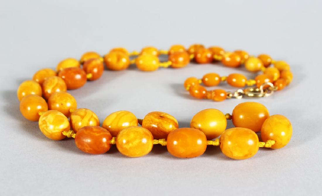 AN EGG YOLK/BUTTERSCOTCH AMBER BEAD NECKLACE, (1 of 2)