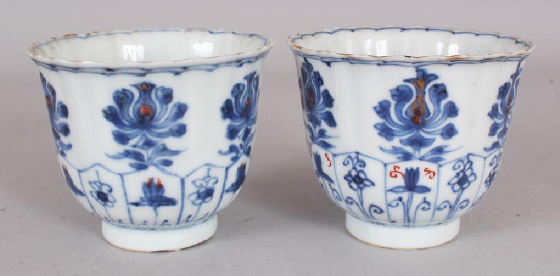 A PAIR OF EARLY 18TH CENTURY CHINESE KANGXI PERIOD: A PAIR OF EARLY 18TH CENTURY CHINESE KANGXI PERIOD UNDERGLAZE-BLUE & IRON-RED DECORATED FLUTED PORCELAIN BEAKERS, each base with a flowerhead mark, 3.5in diameter at rim & 2.8in high.