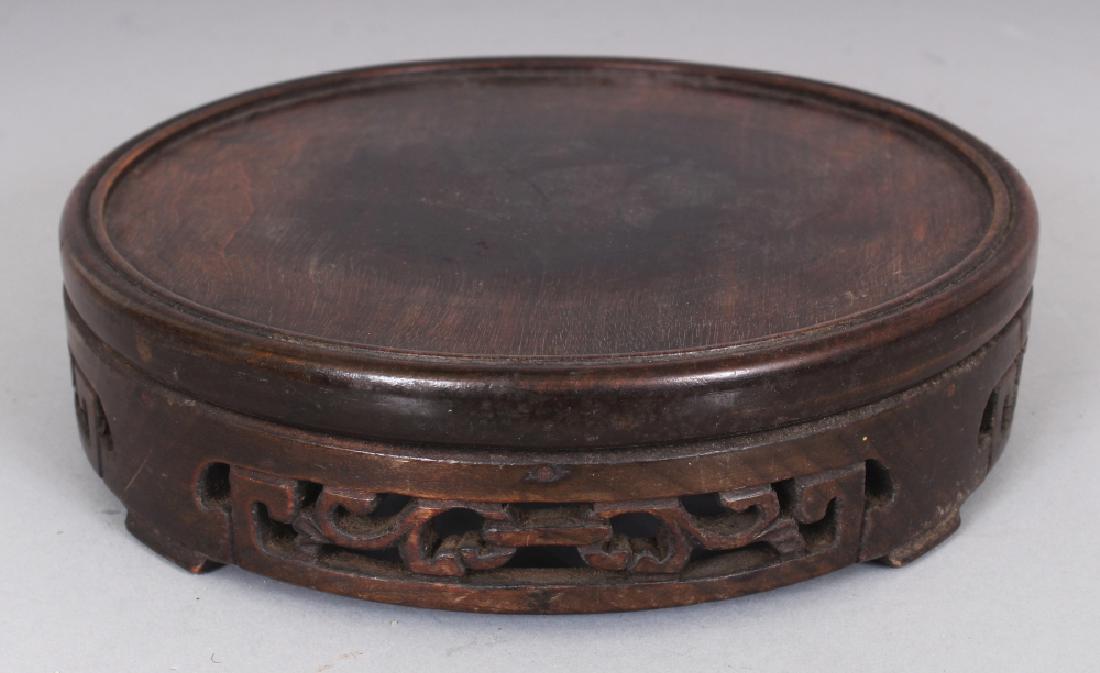 A CHINESE CIRCULAR WOOD VASE STAND, the sides carved (1 of 3)