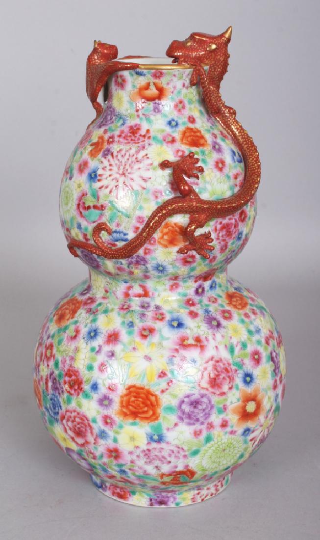 A GOOD QUALITY CHINESE FAMILLE ROSE MILLEFLEUR DOUBLE: A GOOD QUALITY CHINESE FAMILLE ROSE MILLEFLEUR DOUBLE GOURD PORCELAIN VASE, the shoulders and neck moulded in relief with a bat and a chilong peering over the rim, the base with a Qianlong seal mark, 