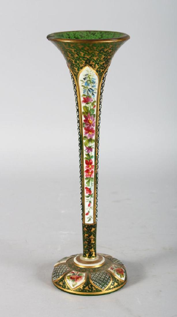 A TALL BOHEMIAN TAPERING GREEN GLASS TRUMPET VASE, with: A TALL BOHEMIAN TAPERING GREEN GLASS TRUMPET VASE, with white enamel decoration and flowers. 12ins high.