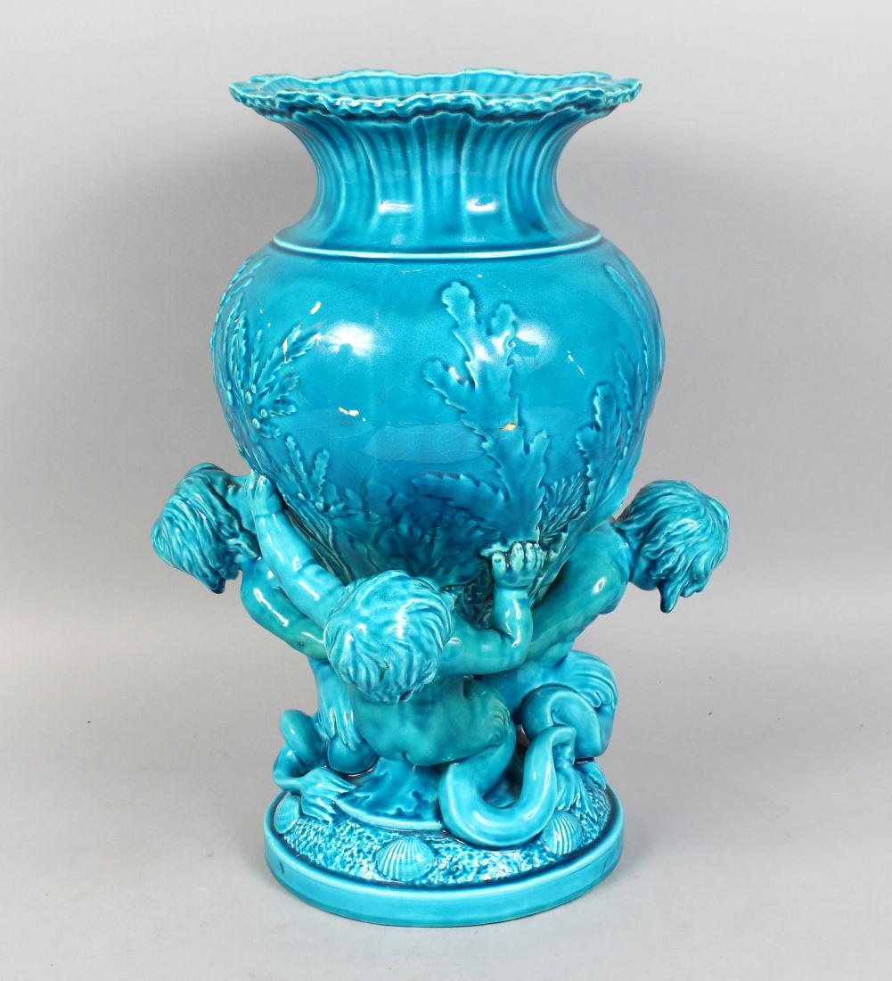 A GOOD LARGE MINTON BLUE GLAZE VASE, held by two cupids: A GOOD LARGE MINTON BLUE GLAZE VASE, held by two cupids on a base with shells. 17ins high.