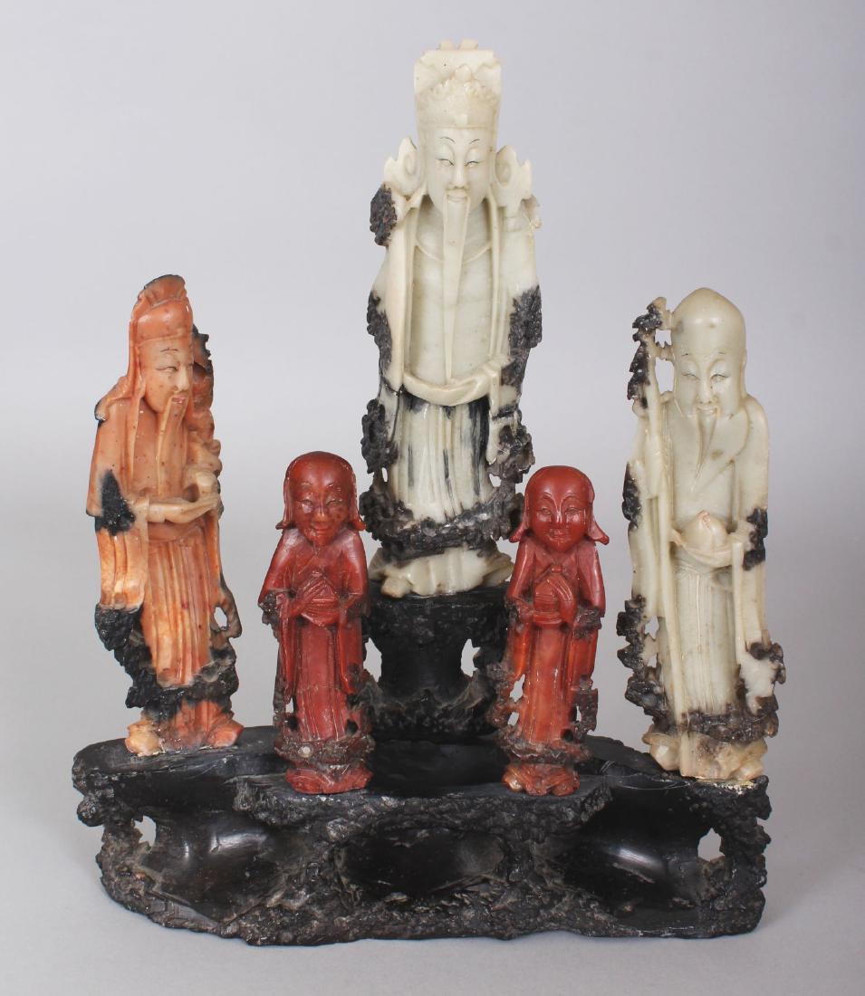 AN UNUSUAL 20TH CENTURY CHINESE SOAPSTONE GROUP OF: AN UNUSUAL 20TH CENTURY CHINESE SOAPSTONE GROUP OF THREE IMMORTALS & TWO BOY ACOLYTES, standing on a separate soapstone stand, 8.8in wide at widest point & 10.75in high overall.