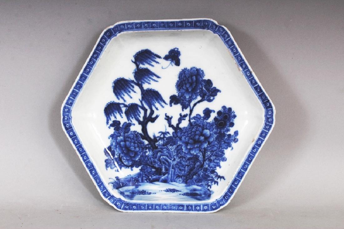 AN 18TH CENTURY CHINESE QIANLONG PERIOD BLUE & WHITE: AN 18TH CENTURY CHINESE QIANLONG PERIOD BLUE & WHITE HEXAGONAL PORCELAIN DISH, the interior painted with a fenced garden scene of peony and other foliage, 8in wide from corner to corner.