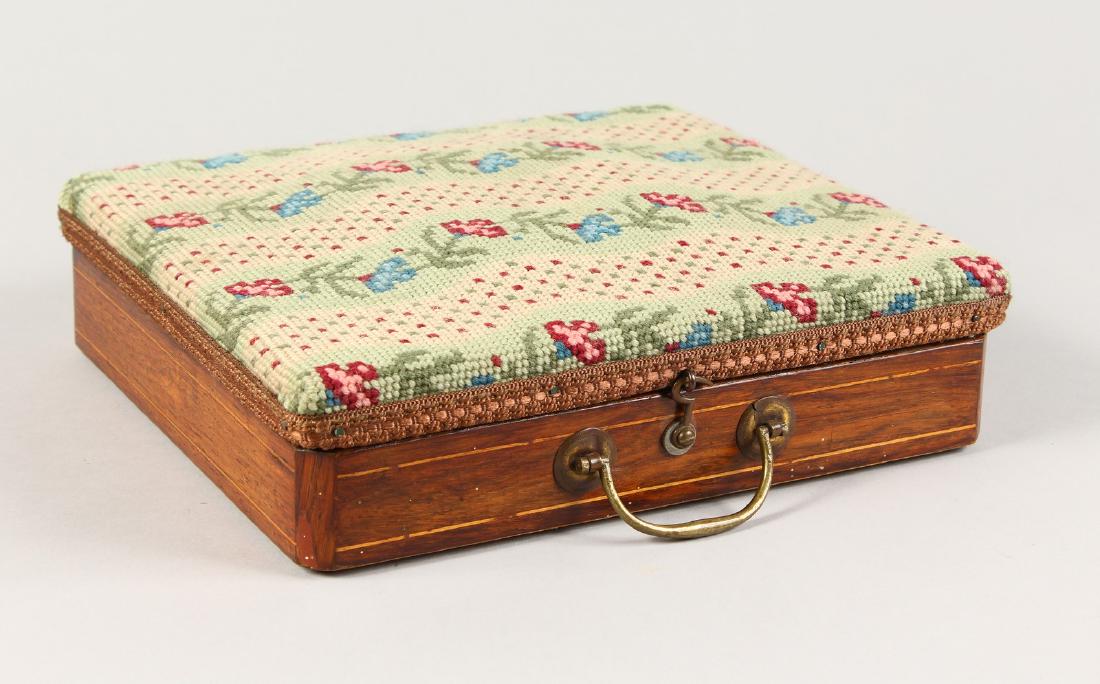A VICTORIAN MAHOGANY INLAID TRAVELLING FOOT WARMER with: A VICTORIAN MAHOGANY INLAID TRAVELLING FOOT WARMER with needlework top, the lid opens to reveal a tin water bottle. 11ins long.