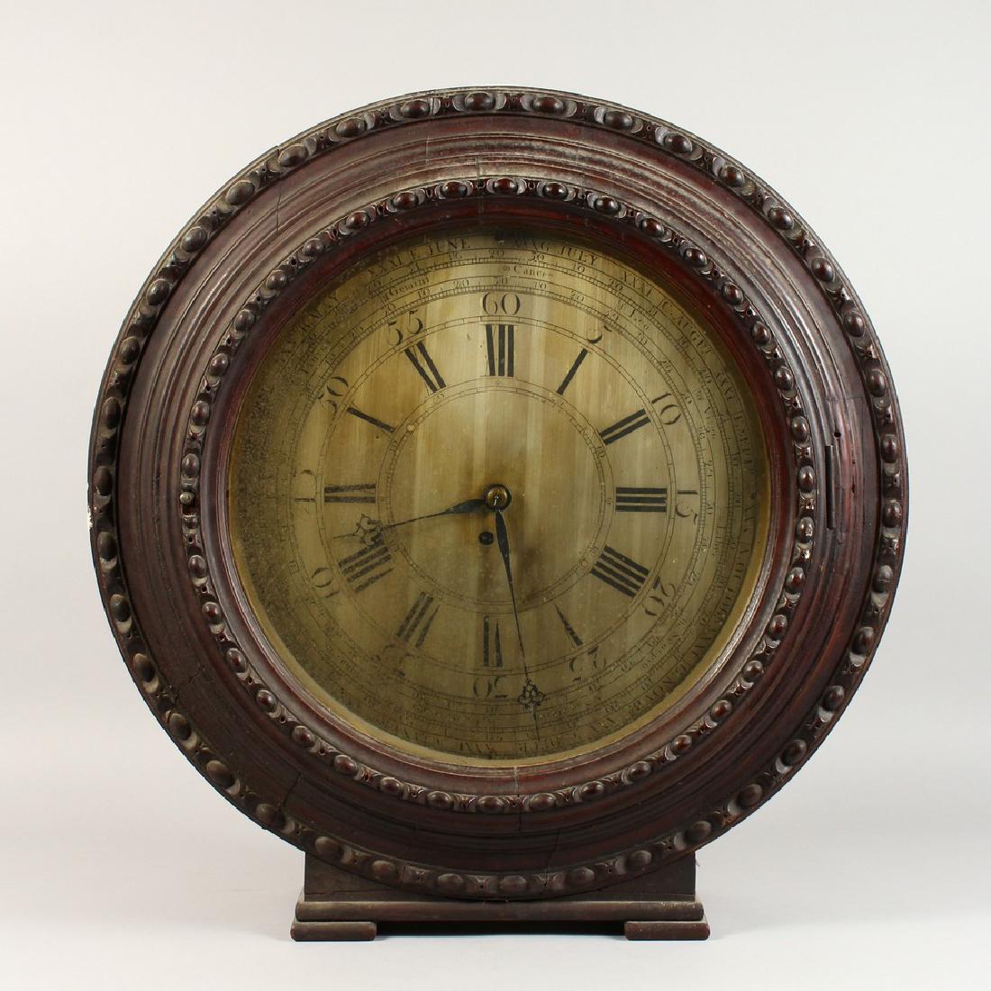 AN UNUSUAL 19TH CENTURY LARGE CIRCULAR WALL/MANTLE: AN UNUSUAL 19TH CENTURY LARGE CIRCULAR WALL/MANTLE CLOCK, the silvered dial engraved with Roman numerals, minutes, months and star signs, housed in a carved mahogany case. 25ins diameter.