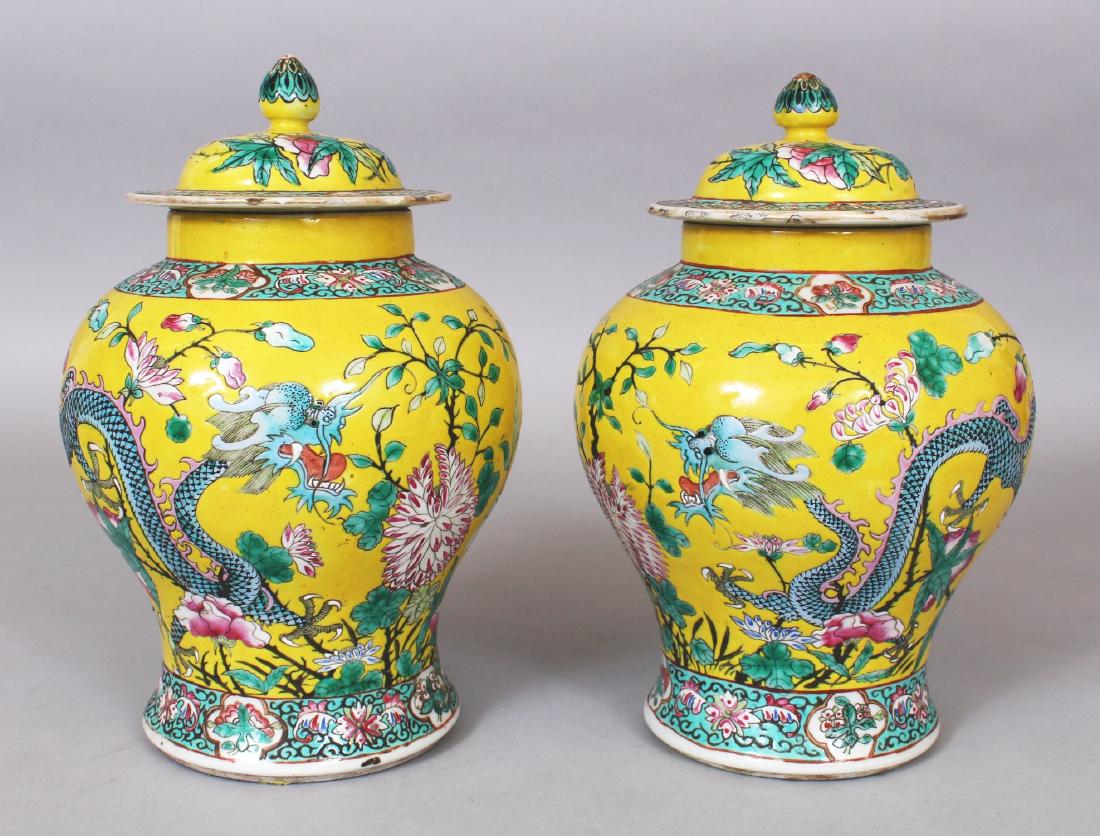 A PAIR OF 19TH CENTURY CHINESE FAMILLE ROSE YELLOW: A PAIR OF 19TH CENTURY CHINESE FAMILLE ROSE YELLOW GROUND PORCELAIN DRAGON JARS & COVERS, each base with a four-character Kangxi mark, 8.5in high overall.