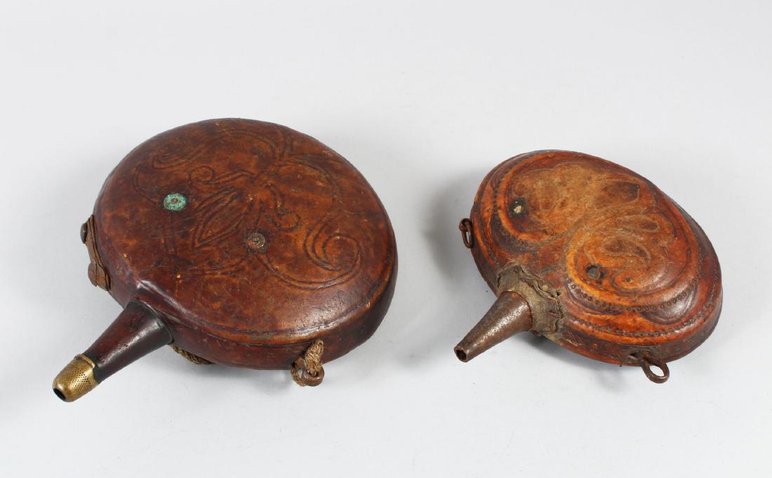 TWO 19TH CENTURY PERSIAN QAJAR LEATHER POWDER FLASKS,: TWO 19TH CENTURY PERSIAN QAJAR LEATHER POWDER FLASKS, Both with embossed fleur-de lys, 22cm x 17cm and 13cm x 16cm.
