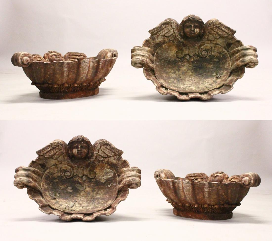A SET OF FOUR CARVED WOOD SHELL SHAPE BOWLS, with angel: A SET OF FOUR CARVED WOOD SHELL SHAPE BOWLS, with angel head decoration. 1ft 9ins wide.
