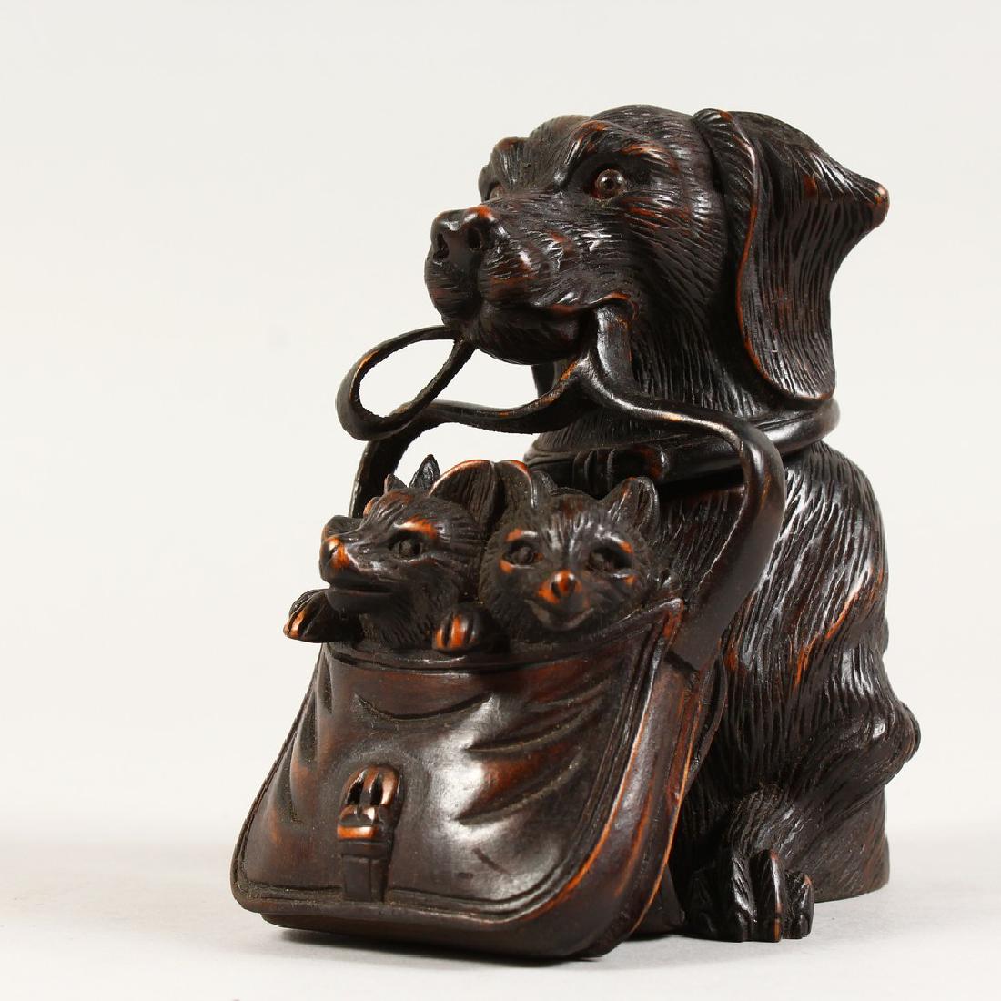 A CARVED WOOD INKWELL, modelled as a dog holding a bag: A CARVED WOOD INKWELL, modelled as a dog holding a bag of puppies in its mouth. 5ins high.