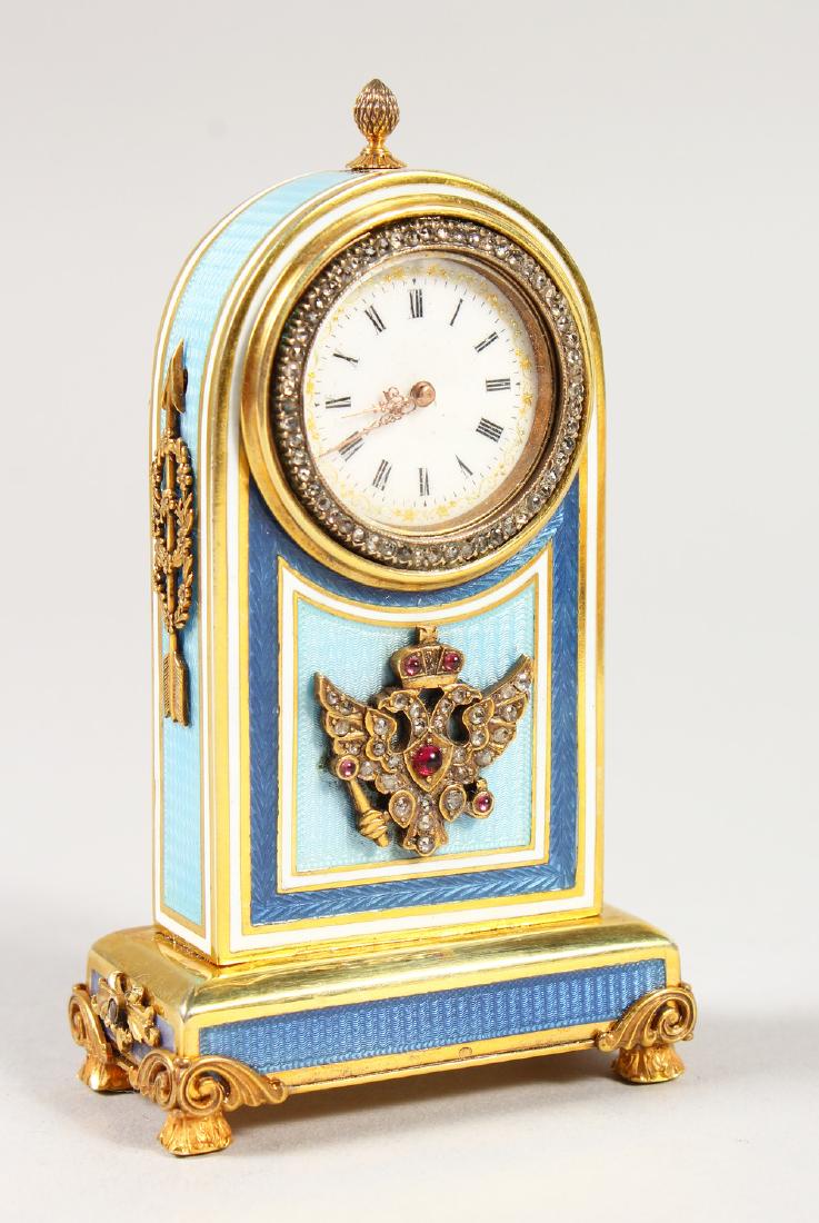 A VERY GOOD SMALL RUSSIAN SILVER GILT AND ENAMEL CLOCK,: A VERY GOOD SMALL RUSSIAN SILVER GILT AND ENAMEL CLOCK, with pale blue and dark blue enamel panels, gem set silver gilt mounts, circular white enamel dial within a diamond set bezel, in a fitted wood 